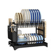 A black double-tier dish rack filled with blue, white, and gold ceramic plates, bowls, cups, and utensils, shown on a plain white background.