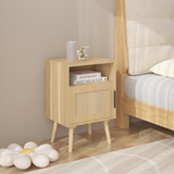 Wooden nightstand next to a bed with books and decorative items on a wooden floor.