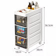 White plastic bathroom organizer cabinet with three transparent drawers and gold handles, shown with dimension labels 56.5cm, 38cm, and 18cm on a light gray background.