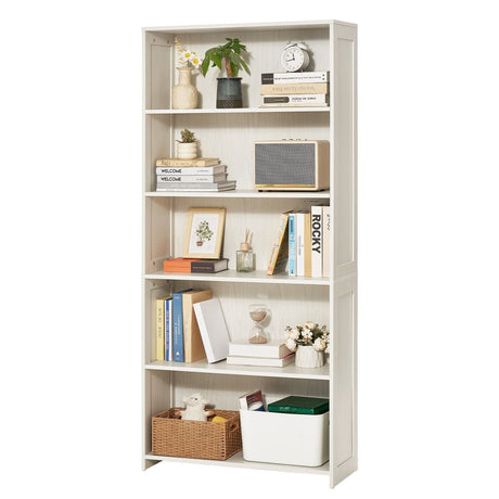 A tall, narrow white bookcase with five shelves, styled with books, vases, a plant, a small radio, a framed print, an hourglass, and storage bins, shown against a plain white background.