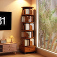 A tall, narrow wooden corner bookshelf with multiple curved shelves holding books, placed in a sunlit room next to a window with blinds and a small side table.