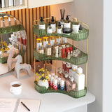 Three-tiered green and gold cosmetic organizer with various products on a desk.